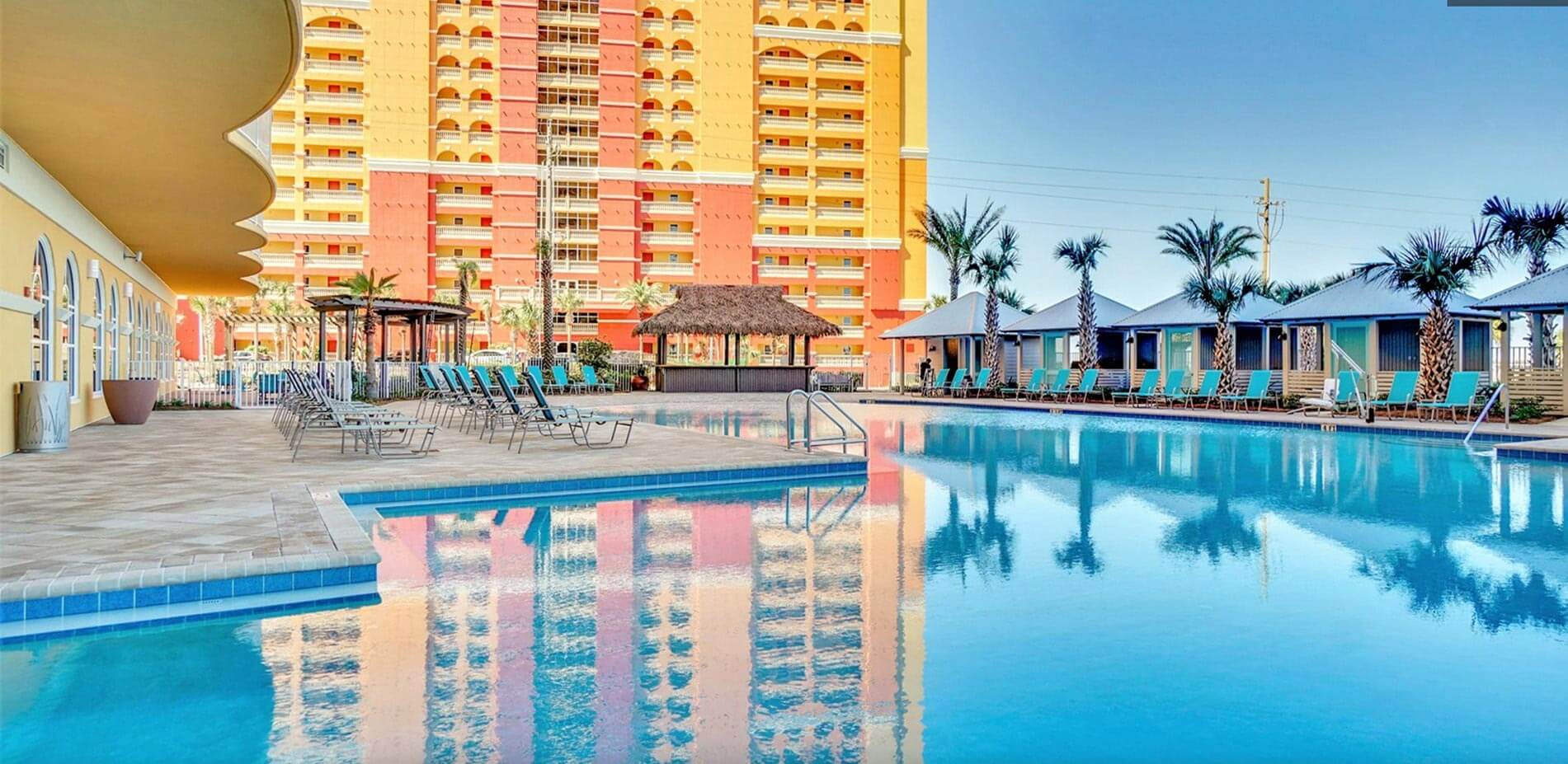 A large outdoor swimming pool with lounge chairs and cabanas